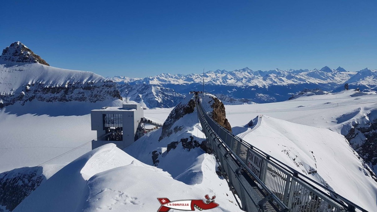 La passerelle Peak Walk entre deux sommets rocheux avec la vue sur les Alpes.
