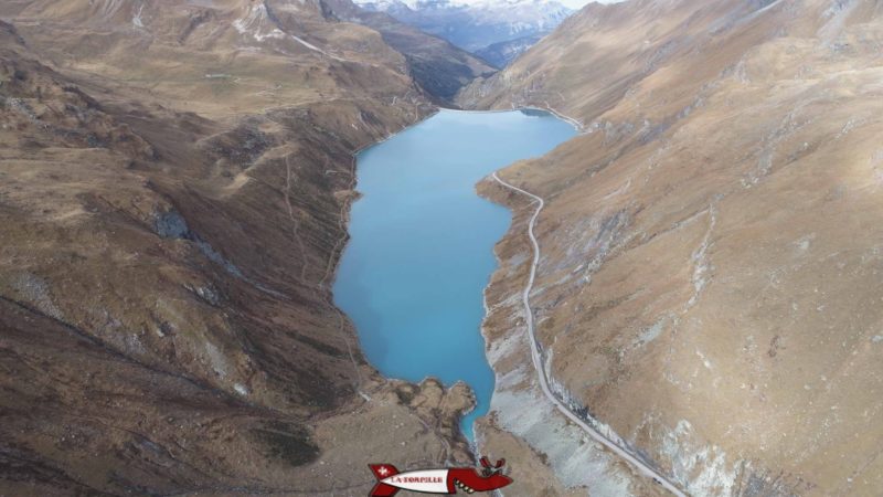 Vue aérienne du lac formé par le barrage de Moiry avec la route et le sentier pour faire le tour du lac.