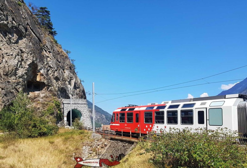 Le train du mont-Blanc Express devant les gorges du Trient. En haut sur la gauche, les embrasures des canons de la partie ouest du fort de Vernayaz.