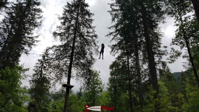 Une personne glissant sur le cable de la tyrolienne du parc des diables