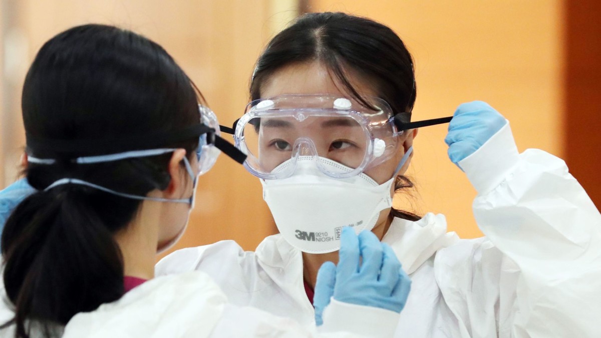 Du personnel medical en train de mettre sa tenue de protection contre le coronavirus avec masque, lunettes et gants.