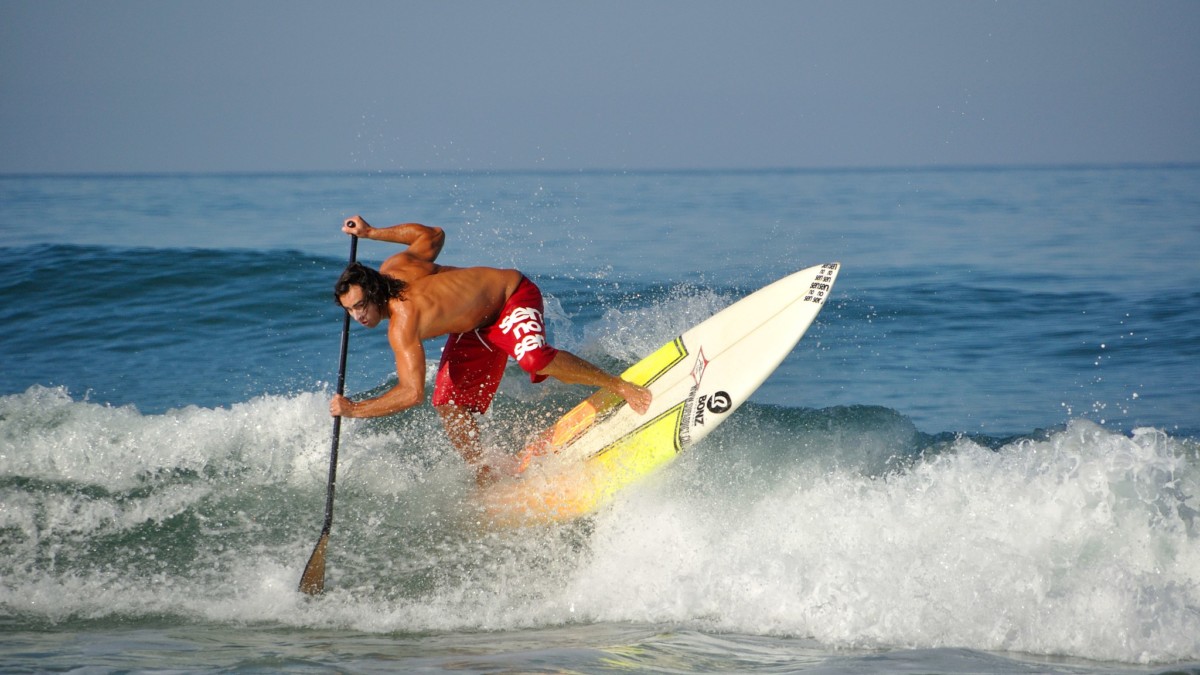 Un paddleur de compétition avec une planche de surf glissant sur un vague. P