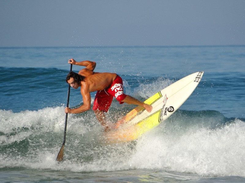 Un paddleur de compétition avec une planche de surf glissant sur un vague. P