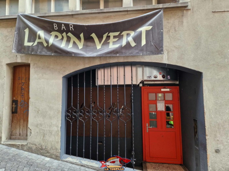 L'entrée du pub Lapin-Vert avec la porte route et du théâtre Lapin-Vert sur la droite avec le grillage noir.