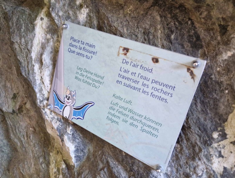 Un panneau qui invite le visiteur à passer sa main à l'intérieur d'une fissure dans la roche pour y ressentir la circulation d'air.