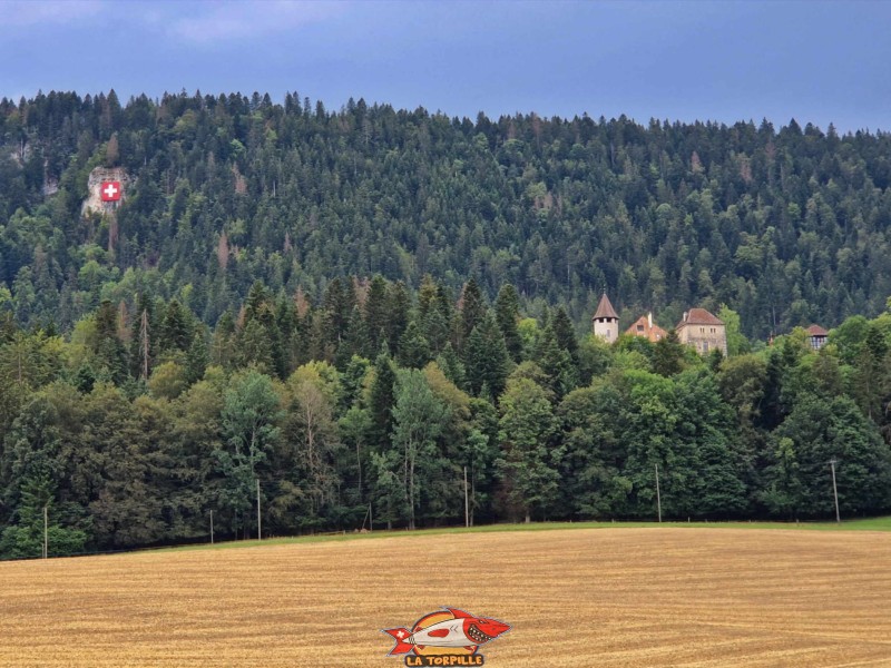 La vue depuis le nord avec le château sur la droite et, sur la gauche, le drapeau suisse de 10 mètes de côté contre le rocher.