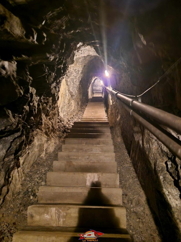En se dirigeant au bout du couloir sud, on peut observer un long escalier qui monte et qui permet d'avoir accès à une sortie de secours.