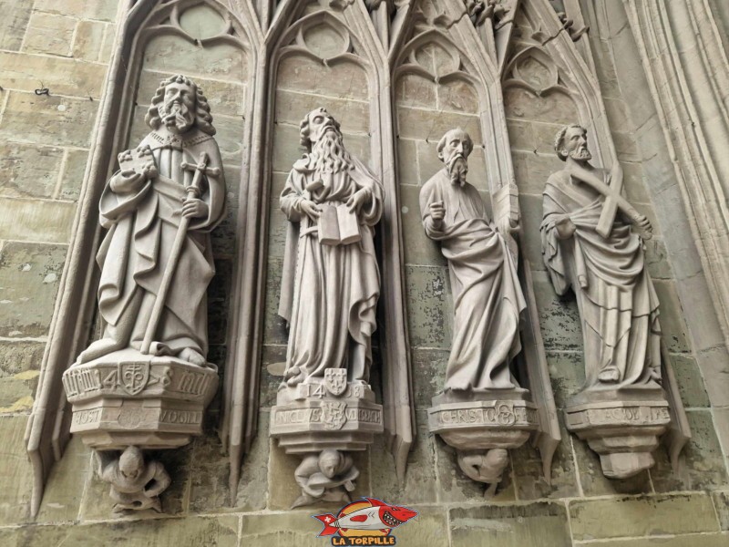 Le portique d'entrée est construit à la fin du 14ᵉ siècle et est orné de sculptures en pierre. Il représente le jugement dernier. Cathédrale St-Nicolas de Myre, Fribourg.