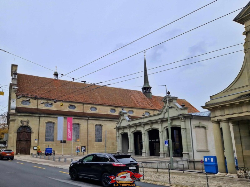 La basilique (droite) se trouve à côté du musée Jean Tinguely et Nikki de Saint-Phalle dans l'ancien hangar des tramways de Fribourg (milieu) et de l'église du couvent des Cordeliers (gauche). basilique Notre-Dame de Fribourg