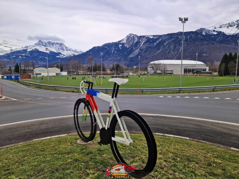 Un vélo au centre du giratoire au nord du centre mondial du cyclisme. À gauche, les Dents du Midi, à droite, le centre mondial du cyclisme. Centre mondial du Cyclisme (CMC) de l'UCI (Union Cycliste international) à Aigle, canton de Vaud.