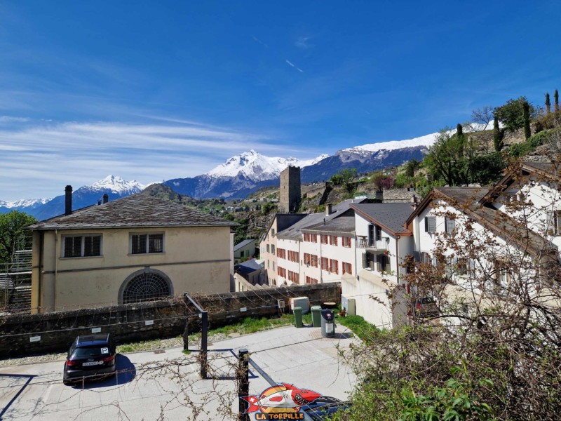 La vue sur la rue des Châteaux depuis la place Maurice-Zermatten. Sur la droite, le centre d'exposition du Pénitencier, et, sur la droite, la tour du Ch