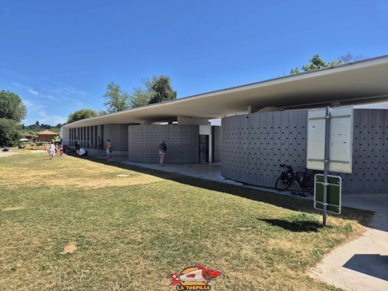 Le long bâtiment à l'entrée où se trouvent des toilettes, des cabines de changement et des douches. nouvelle plage d'estavayer-le-lac, canton de Fribourg, lac de neuchâtel