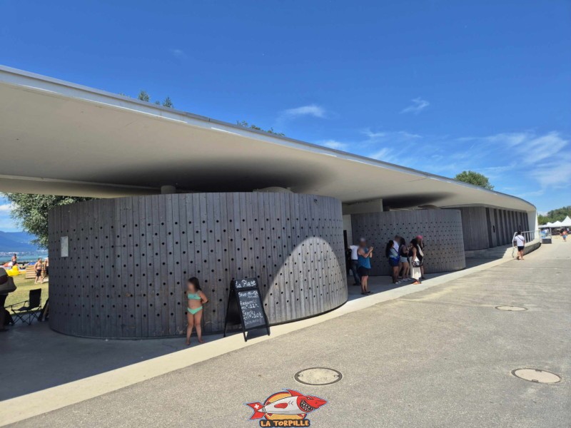 Le long bâtiment à l'entrée où se trouvent des toilettes, des cabines de changement et des douches. nouvelle plage d'estavayer-le-lac, canton de Fribourg, lac de neuchâtel