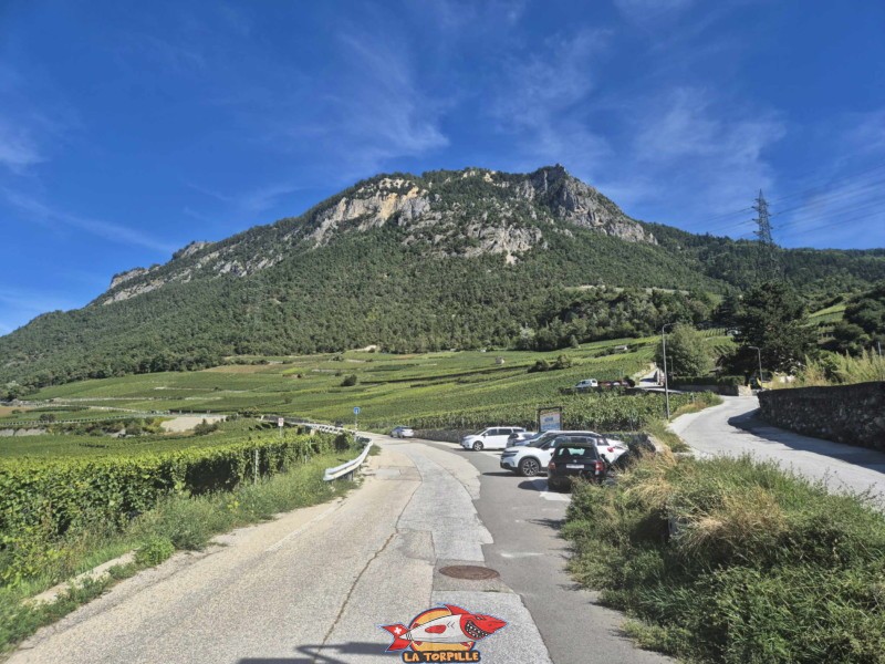 Le parking au bas du vignoble. Les rochers de Nax, avec sur la droite, la via ferrata du Belvédère. Gorges de la Borgne - Val d'Hérens Le parking au bas du vignoble. Les rochers de Nax, avec sur la droite, la via ferrata du Belvédère. Gorges de la Borgne - Val d'Hérens