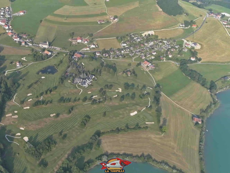 Une vue de drone du golf de la Gruyère. On peut voir le club house du golf ainsi que le village de Pont-la-Ville et son église.