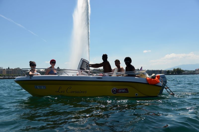 Un bateau à moteur avec le jet d'eau de Genève.