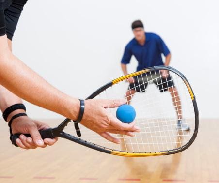 La forme particulière de la raquette de squash avec la balle en caoutchouc.