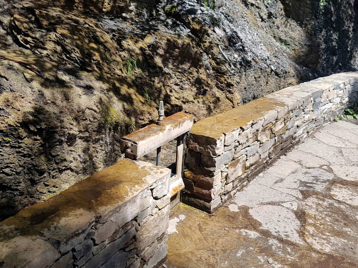 Une porte le long du bisse du Rho. L'élévation de la porte à l'aide d'une vis permet à l'eau de sortir du bisse. Une porte le long du bisse du Rho. L'élévation de la porte à l'aide d'une vis permet à l'eau de sortir du bisse.