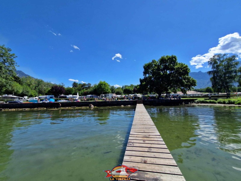 Un long ponton, au bout duquel se trouve une échelle, permet de se baigner dans le lac Léman et son fond sablonneux.