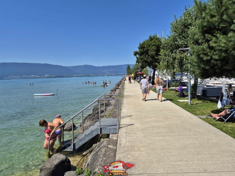 Enrochements. Plage de Chevroux, lac de Neuchâtel, Canton de Vaud. Le chemin de la jetée. On remarque que la toute petite bande de pelouse le long du port est utilisée par les baigneurs en été. Enrochements. Plage de Chevroux, lac de Neuchâtel, Canton de Vaud. Le chemin de la jetée. On remarque que la toute petite bande de pelouse le long du port est utilisée par les baigneurs en été.