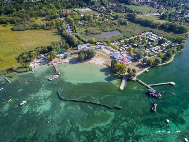 La vue sur la plage avec le camping, la base nautique AlphaSurf et la Grande Gouille au sein de la Grande Cariçaie.