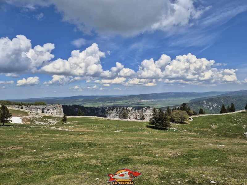 La vue sur le mur de pierre sèche devant le Creux du Van. En arrière-plan, la vallée des Ponts avec, au milieu de l'image, Les Ponts-de-Martel. le mot "Martel" a probablement la signification de "Marteau".