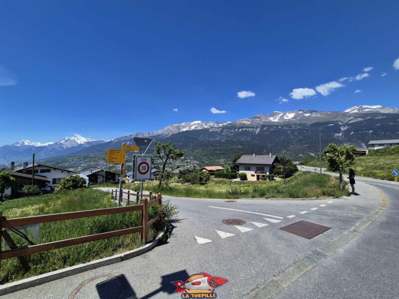 La route d'Icogne qui continue sur la droite. À gauche, le chemin du Lyron utilisé lors du parcours de la petite boucle de 5,1 km. La route d'Icogne qui continue sur la droite. À gauche, le chemin du Lyron utilisé lors du parcours de la petite boucle de 5,1 km. Grand bisse de Lens, Valais central.