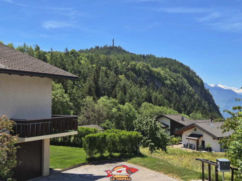 La vue sur la colline du Châtelard au sommet de laquelle se trouve la statue du Christ-Roi. Grand bisse de Lens, Valais central. La vue sur la colline du Châtelard au sommet de laquelle se trouve la statue du Christ-Roi. Grand bisse de Lens, Valais central.