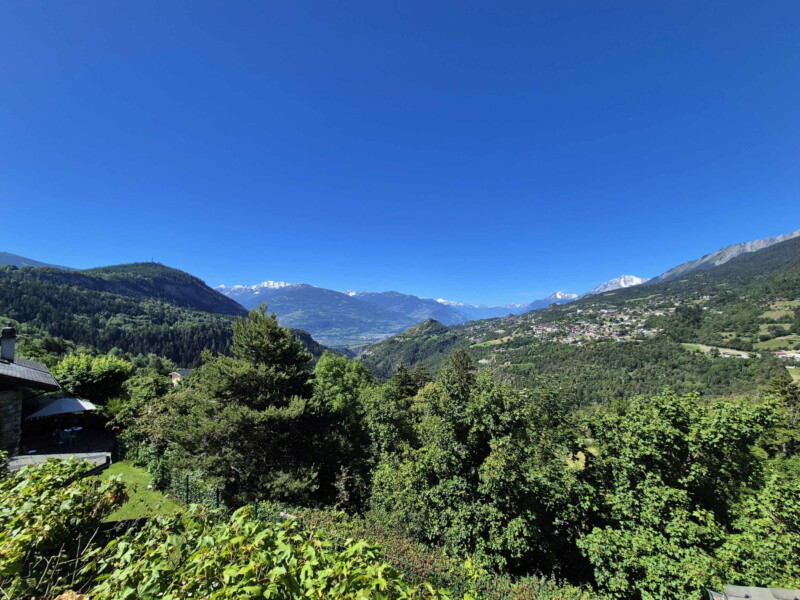 La très belle vue sur la vallée de la Lienne. Sur la gauche, le Châtelard, au sommet duquel se trouve la statue du Christ-Roi. Au milieu la vallée du Rhône. Sur la droite, les villages de Luc, Fortunau et St-Romain (église) qui font partie de la commune d'Ayent.