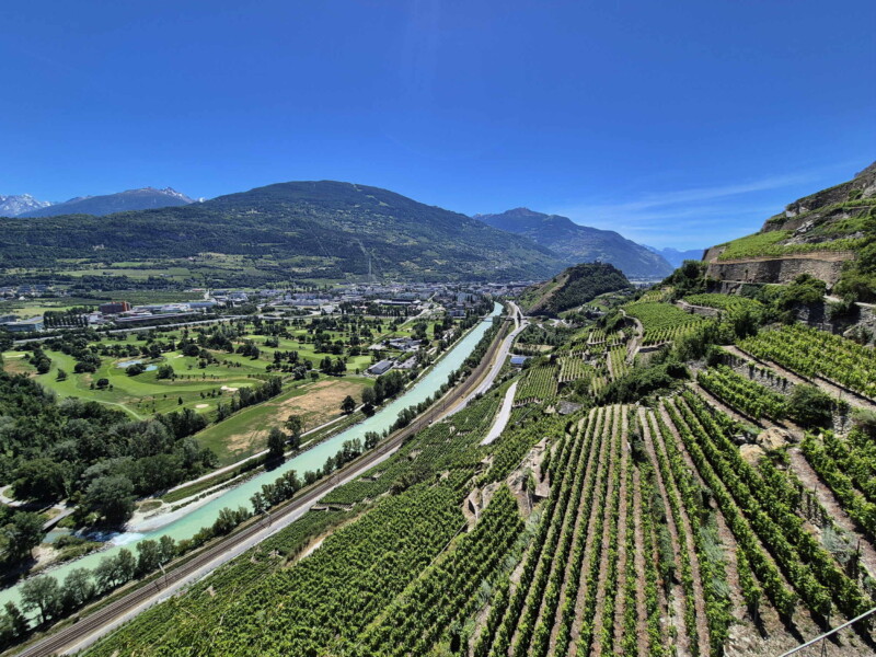 Les coteaux abrupts au-dessous du bisse de Clavau et la vallée du Rhône avec Sion en arrière-plan.