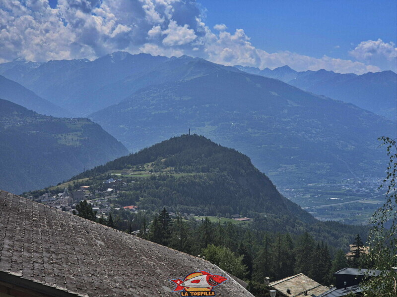 La colline du Châtelard au sommet de laquelle se trouve la statue du Christ-Roi. Montée du bisse - chalets La colline du Châtelard au sommet de laquelle se trouve la statue du Christ-Roi. Montée du bisse - chalets
