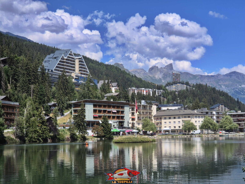 Le zoom sur l'hôtel Crans Ambassador. Le côté Sud de l'étang Grenon. Le zoom sur l'hôtel Crans Ambassador. Le côté Sud de l'étang Grenon.