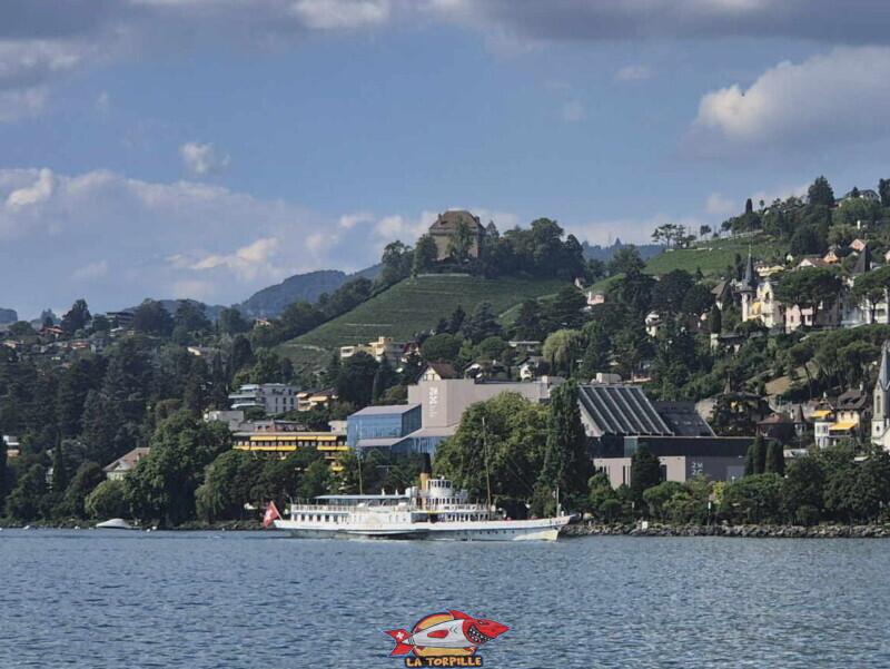 Le zoom sur le château du Châtelard depuis l'esplanade Freddie Mercury de Montreux. Le bateau se trouve au niveau du fameux 2M2C. Le zoom sur le château du Châtelard depuis l'esplanade Freddie Mercury de Montreux. Le bateau se trouve au niveau du fameux 2M2C.