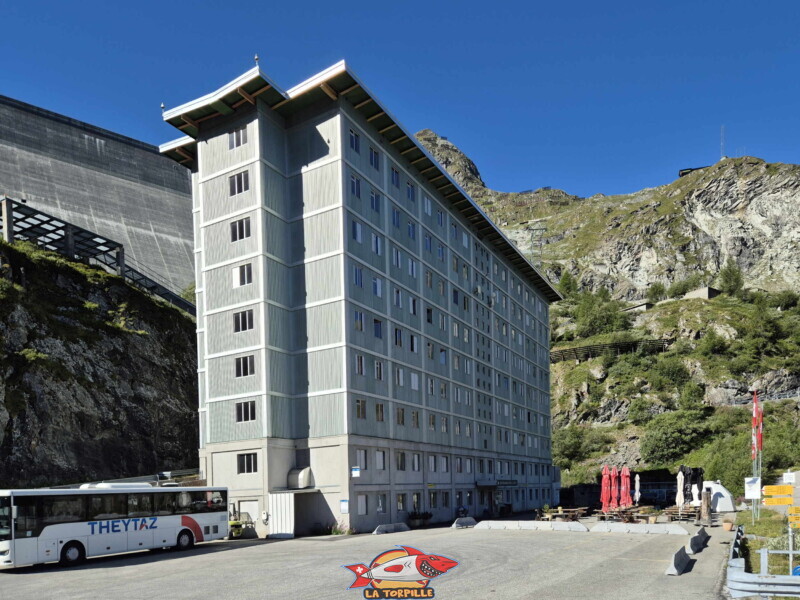 Un car de la société "Theytaz" au pied du barrage. Barrage de la Grande Dixence, Hérémence, canton du Valais. Un car de la société "Theytaz" au pied du barrage. Barrage de la Grande Dixence, Hérémence, canton du Valais.