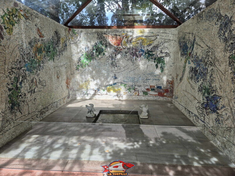 La chapelle à ciel ouvert abritant d'immenses et éclatantes mosaïques murales de Marc Chagall. Intitulée Le Couronnement de la Vierge, cette œuvre entoure un petit bassin d'eau central et met en scène l'univers poétique et coloré du peintre.