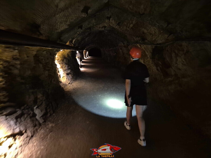 Une visiteuse équipée d'une lampe de poche. Visite des mines. Mines d'Asphalte de la Presta - Val-de-Travers, canton de Neuchâtel. Une visiteuse équipée d'une lampe de poche. Visite des mines. Mines d'Asphalte de la Presta - Val-de-Travers, canton de Neuchâtel.