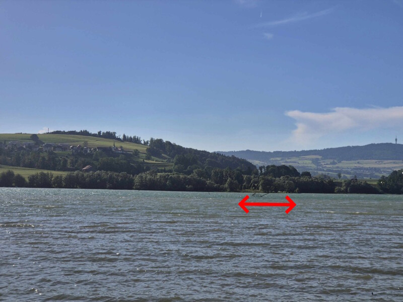 La plage de la pointe (en rouge) depuis la plage de Botterens. Sur la gauche, le village de Morlon, sur la droite, l'antenne du Mont-Gibloux.
