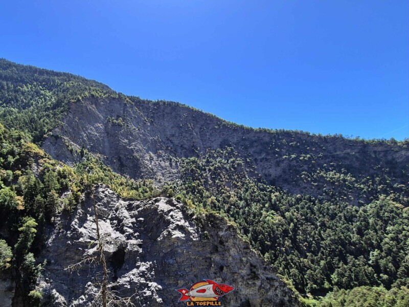 La vue sur les falaises de la rive gauche de la Lienne depuis le bisse de Clavau. On peut remarquer la trace horizontale au milieu de l'image du bisse du Sillonin. Zone vertigineuse, paroi rocheuse. La vue sur les falaises de la rive gauche de la Lienne depuis le bisse de Clavau. On peut remarquer la trace horizontale au milieu de l'image du bisse du Sillonin. Zone vertigineuse, paroi rocheuse. Bisse de Sillonin